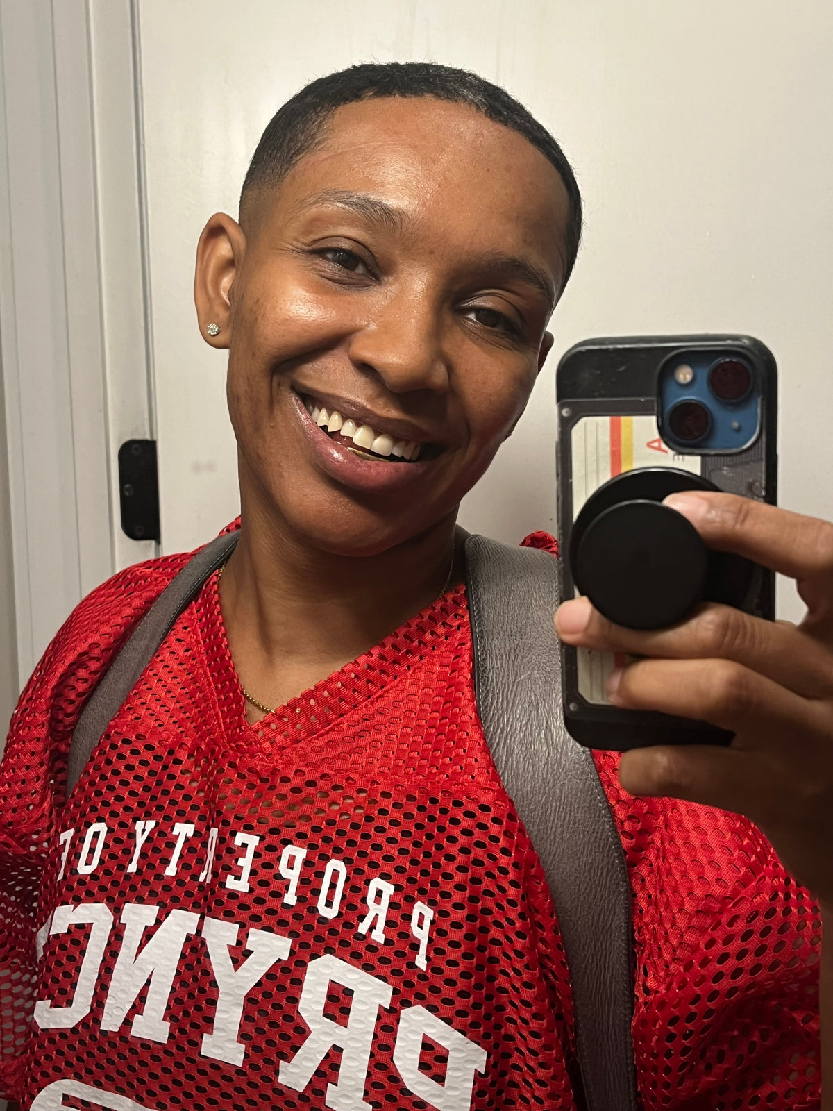 Red '85 Practice Jersey with gold print, worn over a white tee in a mirror fit photo